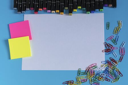 Multi-colored markers, paper clips, stickers and paper on a blue background. Drawing and creativity.の写真素材