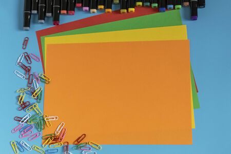 Multi-colored markers, paper clips, stickers and paper on a blue background. Drawing and creativity.の写真素材