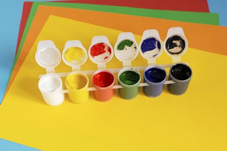Stack of multi-colored paper and paint for drawing on a blue background.の写真素材