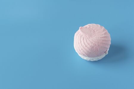 Pink and white sweet air marshmallows on a blue background. Delicate dessert.の写真素材