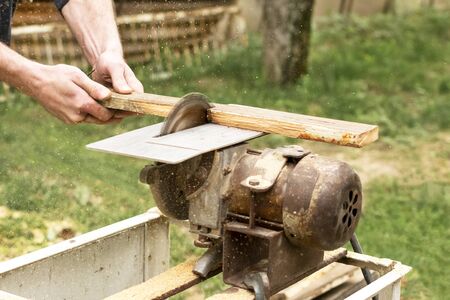 Construction contractor worker using a worm-driven hand-held circular saw to cut boards.