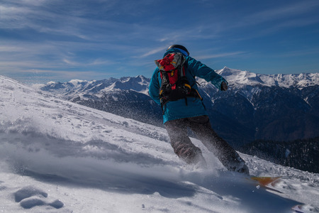 Snowboarder rides fast on loose snow Freeride. Leaves a beautiful pillar of snow. Rosa Khutor,...