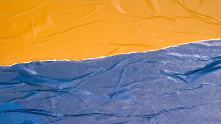 Empty crumpled and wet texture paper. Creased grunge paper background. Art rough stylized blank for a billboard, poster or banner with space for text. Copy space. Collage of yellow and blue.の写真素材