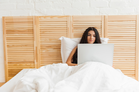 Young woman surfing on the internet in her bedroomの写真素材