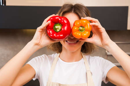 Funny picture of a woman holding big papricas in front of her faceの写真素材