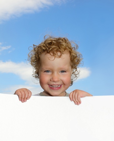Curly girl with empty blank, against the skyの写真素材