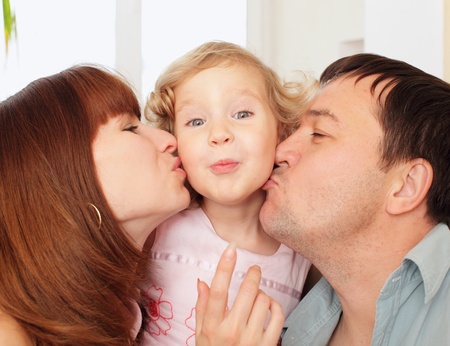 Portrait happy parents kissing the daughterの写真素材