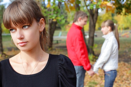 Sad young woman against happiness coupleの写真素材