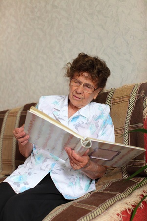 Lonely elderly woman looks a family picture albumの写真素材