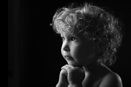 Praying little girl isolated on black Backgroundの写真素材