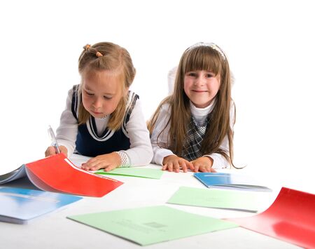 Two schoolgirls with writing-books on a white backgroundの写真素材
