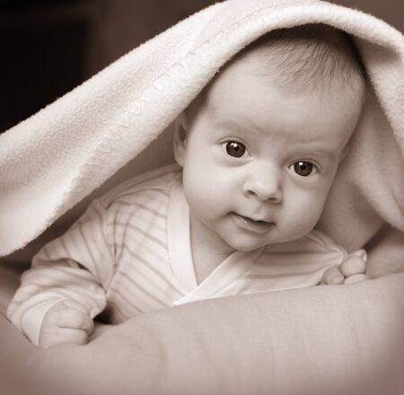 Beautiful baby under pink blanketの写真素材