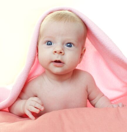 Beautiful baby under pink blanketの写真素材