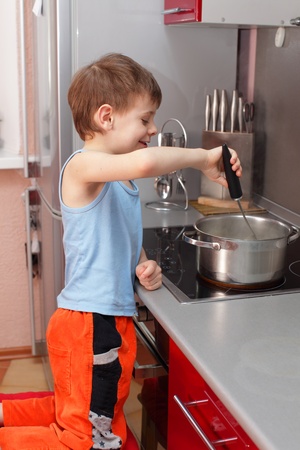 Little boy cooking porridge in kitchenの写真素材