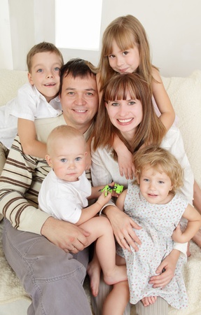 Happy family with four children on sofaの写真素材