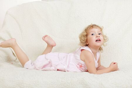 Little happy girl of the house on a sofaの写真素材