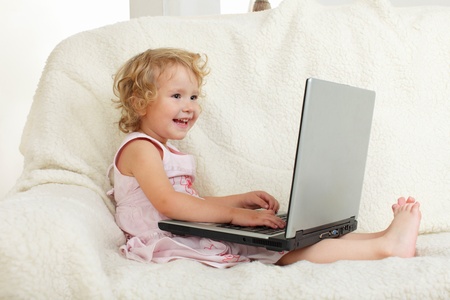 Little girl with laptop at homeの写真素材