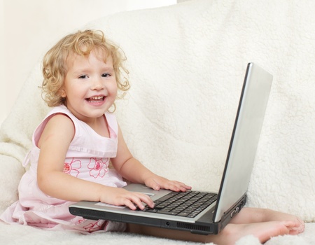 Little girl with laptop at homeの写真素材