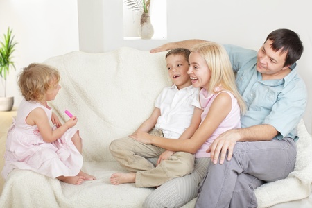 Happy family with two children on sofaの写真素材