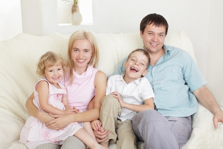 Happy family with two children on sofaの写真素材