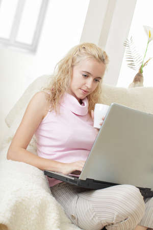 Young woman with laptop and a coffee cup at homeの写真素材