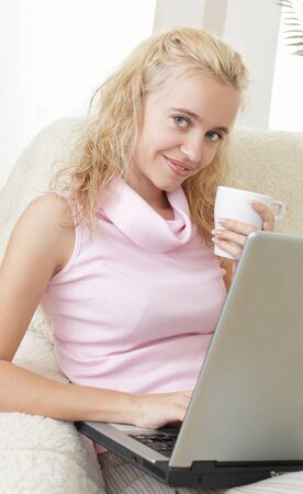 Young woman with laptop and a coffee cup at homeの写真素材