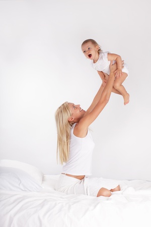 Mother with baby playing on bedの写真素材