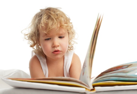 Baby reading book on the bedの写真素材