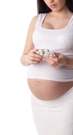 Pregnant woman holding pills isolated on whiteの写真素材