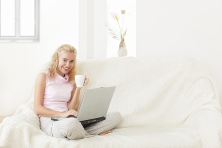 Young woman with laptop on a sofaの写真素材