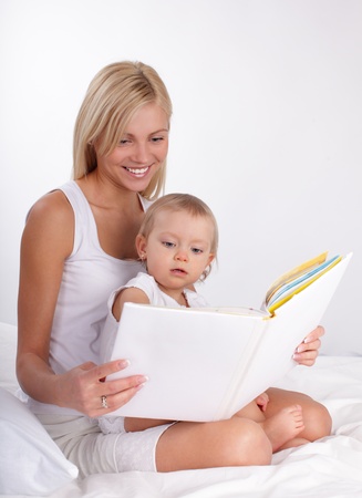 Mother reading book to a daughter at homeの写真素材