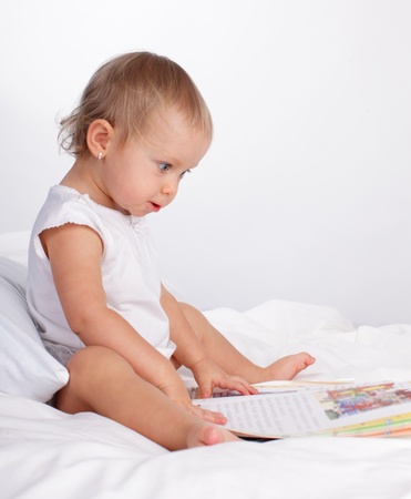 Baby reading book on the bedの写真素材