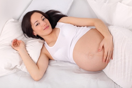 Happy pregnant woman on bedの写真素材