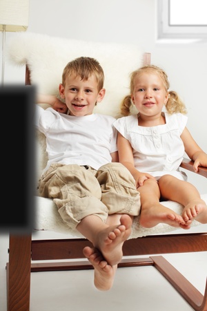 Brother and sister watching TV at homeの写真素材