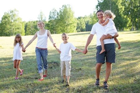 Happy family with three children walking on parkの写真素材