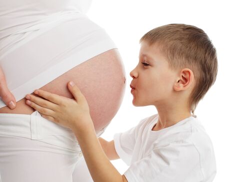 Ñhild a kissing stomach of pregnant mother isolated on whiteの写真素材