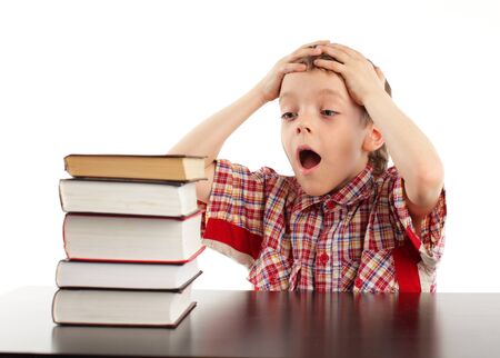 Shocked schoolboy looks at books isolated on whiteの写真素材