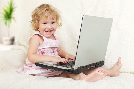 Little girl with laptop at homeの写真素材