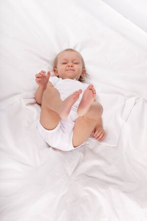 Blue-eyed baby in bedの写真素材