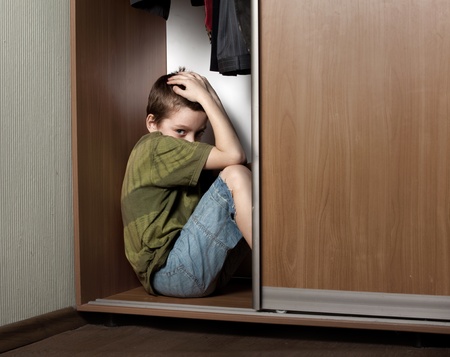 Sad boy, hiding in the closet at homeの写真素材