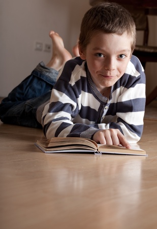 Child reeding book lying on the floorの写真素材