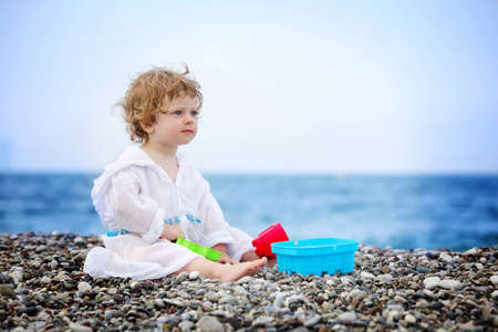 Baby on the beach in white dressの写真素材