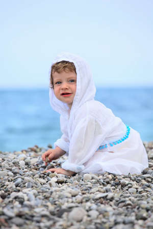 Baby on the beach in white dressの写真素材