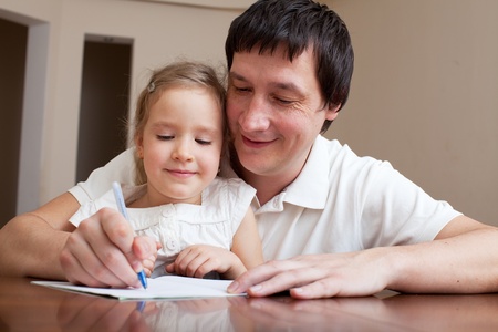 Father helping daughter doing homework. Parent with child writingの写真素材
