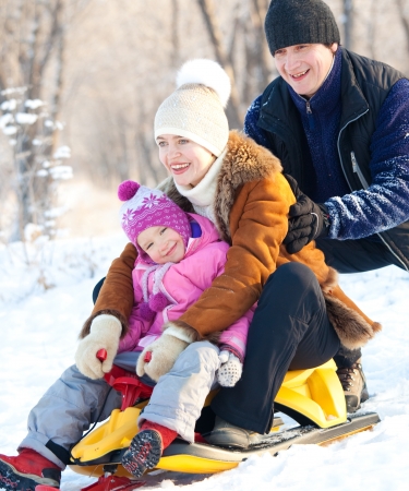 Family sledding in a winter park. Parents with child on sledの写真素材