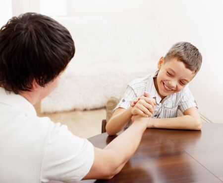 Father and son arm wrestling. Dad play with childの写真素材