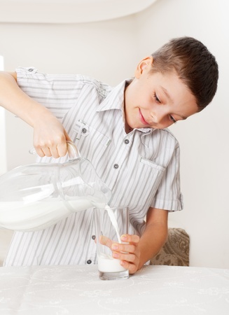Child with glass pitcher milk. Boy drinking milk for breakfastの写真素材