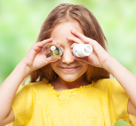 Child with bulbs. Girl holding an energy-saving and incandescent lampの写真素材