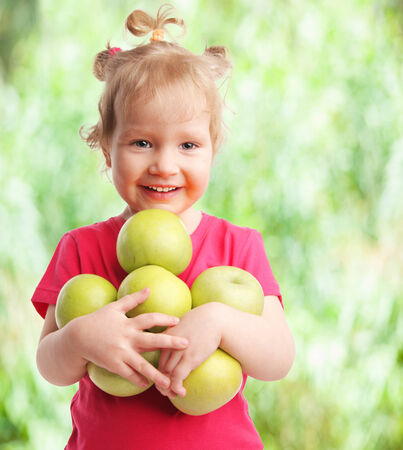 Happy little girl with apples outdoorsの写真素材