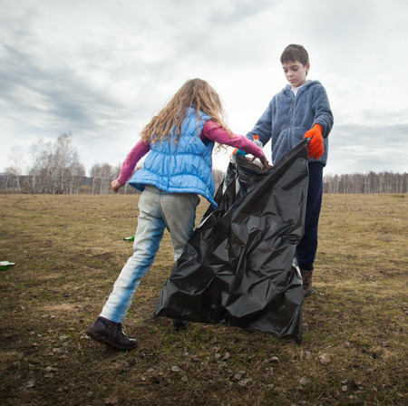 Children cleaning scavenge. Children collect garbage bag in the woods